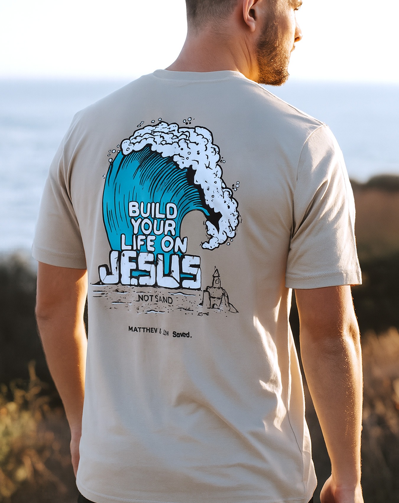 Chrześcijańska koszulka z motywem fali i napisem Build Your Life on Jesus, not sand. Marki Saved.